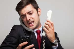 32259023 - stressed businessman talking on many phones at once