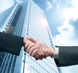13278327 - business handshake with modern office skyscraper
